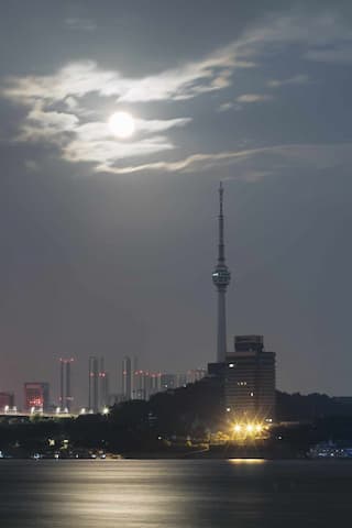 夜晚城市景观，有塔，建筑群，水面反射光线，天空有月亮和云彩