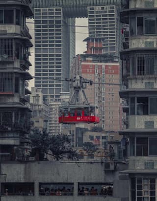 红色缆车在城市建筑群中运行 高楼大厦背景 缆车内有人影