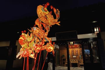 图片展示了夜晚悬挂的多个鱼灯，背景是传统风格的建筑。