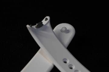 两条白色表带交叉放置在黑色背景上 表带上有孔洞和连接部件