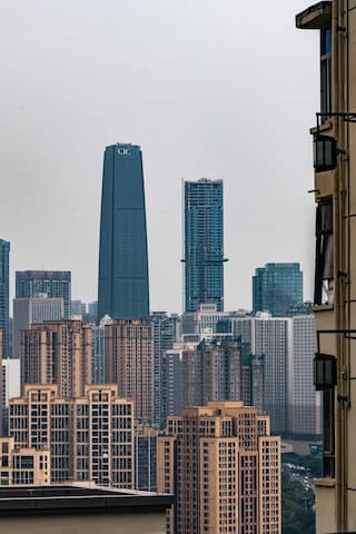 图片展示了城市景观 远处可见高耸的现代建筑 近处是居民楼 整体呈现出城市风貌