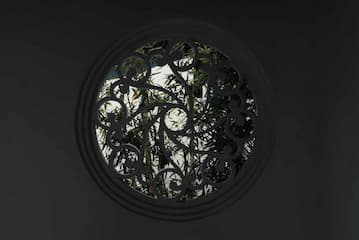 圆形镂空窗户 窗外可见竹子等植物 整体光线较暗