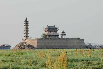 湖中一座古城墙上有塔和亭子周围是绿色的草地