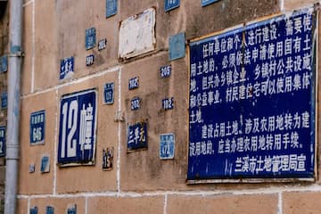 墙面上贴着各种牌子 其中一块是关于土地使用的告示 还有一些是数字编号的牌子