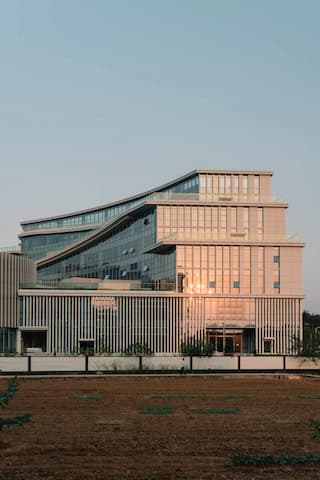 图片展示了一座现代建筑，具有多层结构和玻璃幕墙，反射着光线。