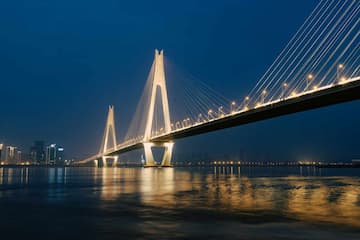 一座桥梁横跨水面夜幕降临灯光照亮桥身和城市天际线