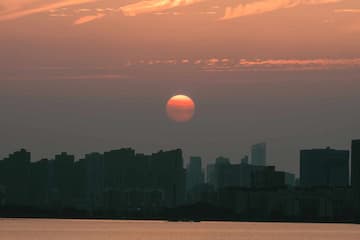 夕阳西下 城市天际线被染成橙色 水面平静 反映着天空的色彩