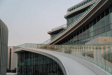 图片展示了一座具有流线型设计的现代建筑，建筑外立面主要由玻璃幕墙构成。
