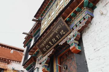 图片展示了一栋具有藏式风格的建筑，建筑外观色彩鲜艳，门牌上有藏文。