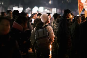夜晚人群聚集 有人戴着白色帽子 背着背包 气氛热闹