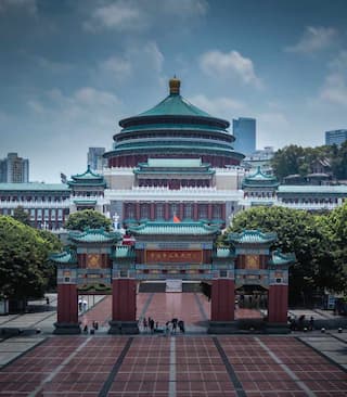 宏伟的中国传统建筑风格礼堂 广场上有少量人群 建筑在蓝天白云下显得庄严