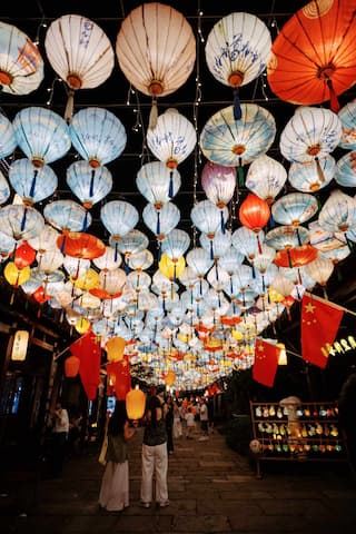 街道上方悬挂着许多灯笼，还有中国国旗，人们在街上行走。