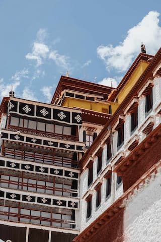 拍摄的是一座具有藏式风格的建筑，建筑主体颜色是红白黄三色，背景是蓝天白云。