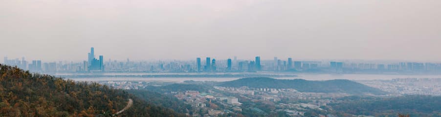 远景拍摄城市天际线 雾气笼罩 远处高楼林立 近处山峦起伏 植被覆盖