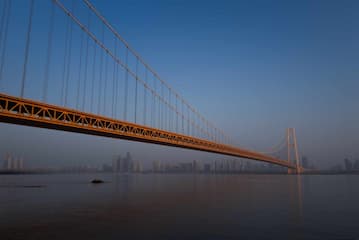 一座桥梁横跨水面远处是城市的天际线天空湛蓝