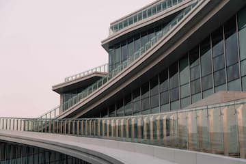 图片展示了一座现代建筑的局部，建筑外立面以玻璃幕墙和曲线结构为主要特征。