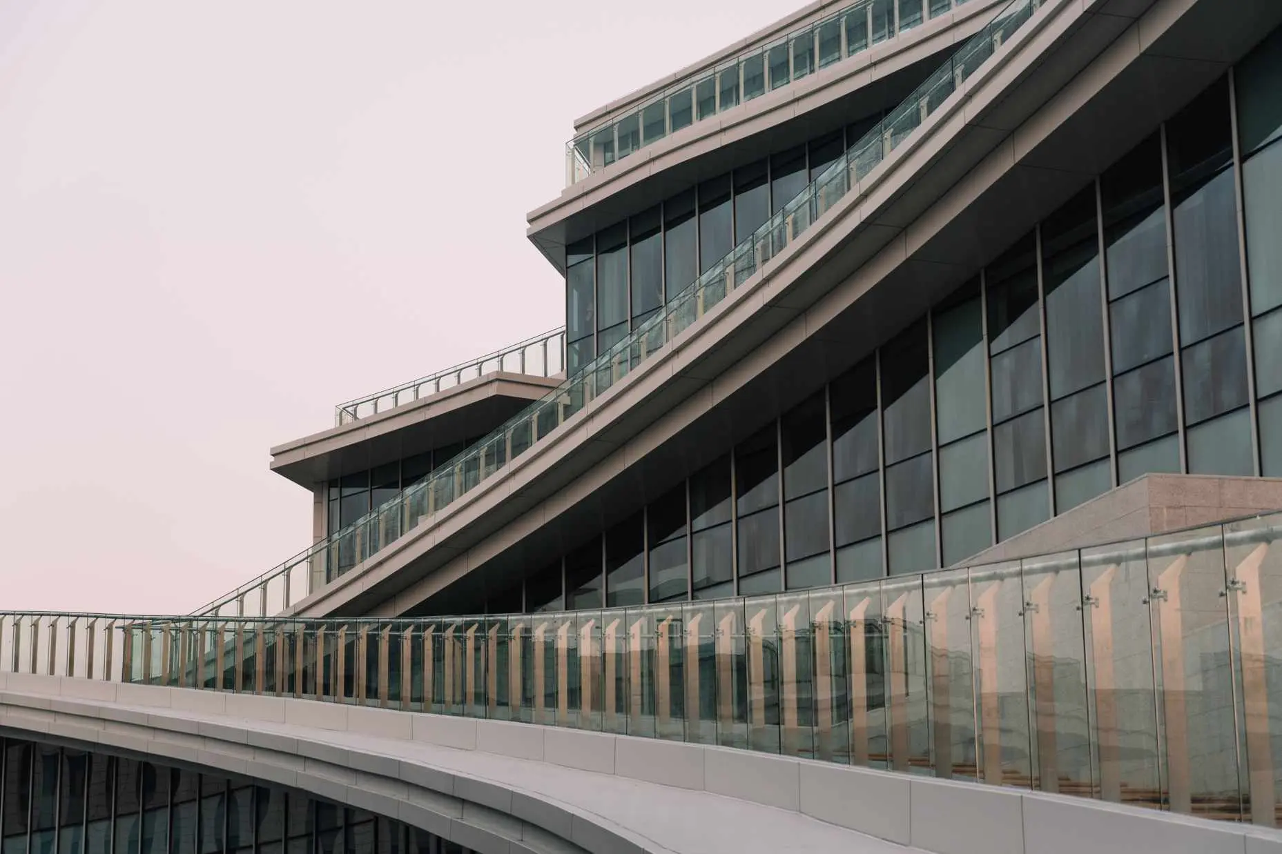图片展示了一座现代建筑的局部，建筑外立面以玻璃幕墙和曲线结构为主要特征。
