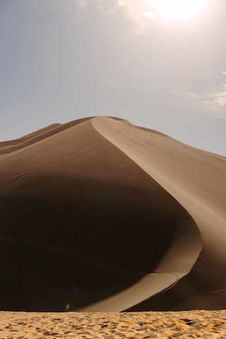 图片展示了一个沙漠景观 沙丘的曲线在阳光下形成阴影 展现了沙漠的壮丽和宁静