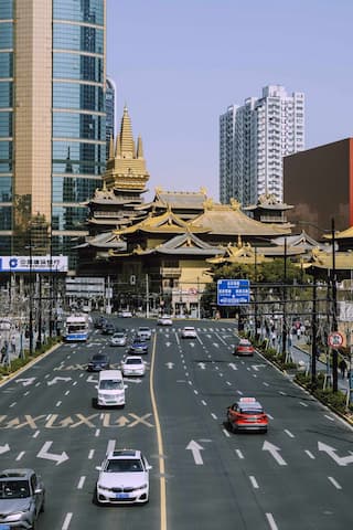 繁忙的城市道路上车辆行驶远处是高楼大厦和一座金色的寺庙建筑