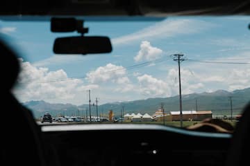 透过车窗看到蓝天白云下的建筑群和远山